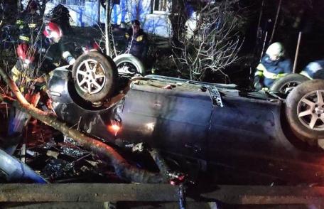 Accident! Un bărbat a rămas încarcerat după ce a lovit un copac și s-a răsturnat cu mașina într-o curte - FOTO